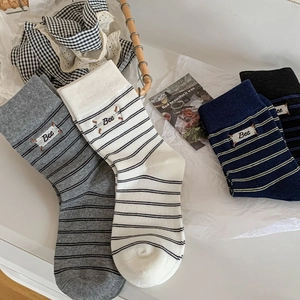 Dettaglio della trama a maglia di calze a righe con etichette Bee ricamate in quattro colori