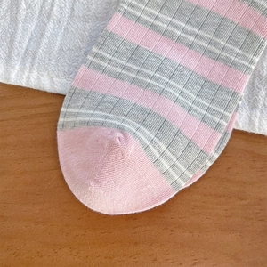Dettaglio ravvicinato di calze a righe rosa e grigie con trama a maglia fine e cuciture