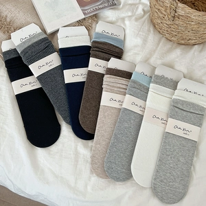 Close-up of assorted color ribbed cotton socks with minimalist brand packaging cards