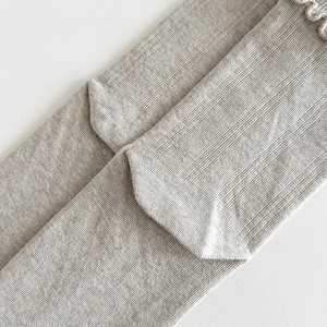 Dettaglio di calze in maglia grigio melange con bordo a balze e trama a coste sottili