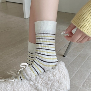 Close-up of white ribbed cotton socks with yellow and brown stripes on model