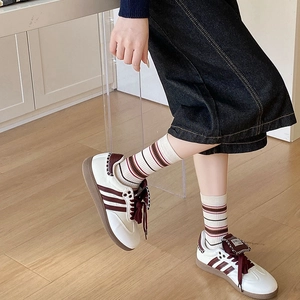 Close-up of retro cream sneakers with burgundy stripes and casual striped crew socks
