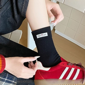 Detail of black ribbed crew socks featuring a woven side label and minimalist knit texture