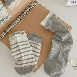Close-up of cute grey striped and solid mid-calf socks with frilly ruffle edges