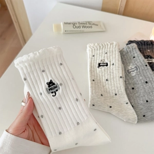 Detailed view of cat embroidery and ruffled cuffs on cotton knit polka dot crew socks