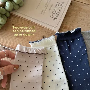 Détail de chaussettes à pois rétro avec bords à volants en beige, blanc et bleu marine