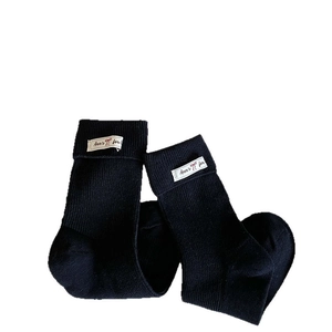 Solid ribbed crew socks for women with white fabric label and bow detail on the cuff
