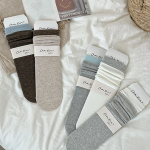 Flat lay of ribbed knit slouch socks in diverse neutral tones with minimalist packaging