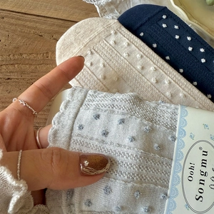 Close-up of cotton socks with vertical stripes, pom-poms, and ruffled cuffs on wood