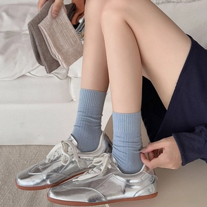 Close-up of ribbed cotton crew socks in pastel blue, khaki, and brown with casual sneakers