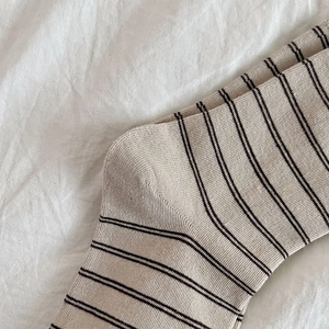 Detailed close-up of ribbed texture and black stripes on cream cotton mid-tube socks