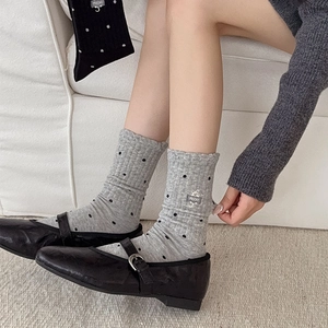 Detailed close-up of cat embroidery and black polka dots on light gray knitted socks