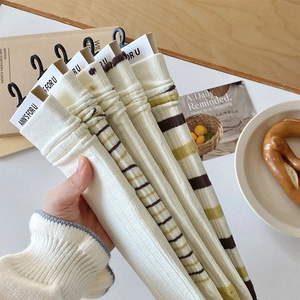 Set of five cream crew socks with green and brown stripes on a wooden table