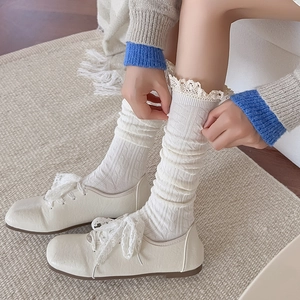 Detailed close-up of white calf socks with lace trim and vertical ribbed knit texture