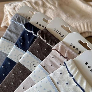 Détail de cinq paires de chaussettes à pois avec bords ondulés en couleurs neutres