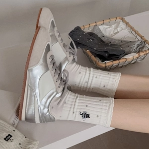 Close-up of retro silver sneakers with knitted mid-calf socks featuring cat embroidery