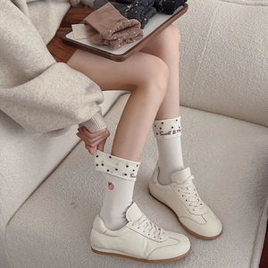 Detail of white cotton crew socks with polka dot cuffs and sweet strawberry embroidery