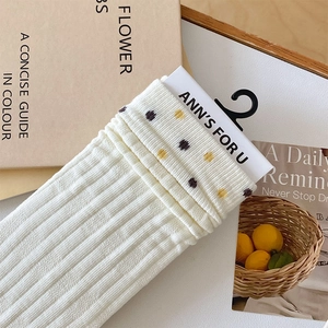 Detailed close-up of white ribbed crew socks featuring colorful polka dots and packaging