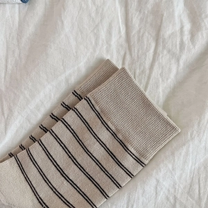 Macro shot of minimalist beige and black striped cotton socks with ribbed cuffs