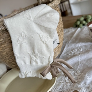 Detailaufnahme weißer Strickstrümpfe mit Blumenmuster, Rüschen und brauner Schleife