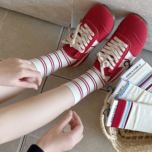 Detail of red and white striped mid-tube socks paired with red suede sneakers and more socks