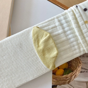 Close-up of white ribbed knit socks with yellow heel and dark polka dot cuff details