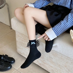 Detail schwarzer Wadensocken mit Spitzensaum und blau karierter Schleife zu Lederschuhen