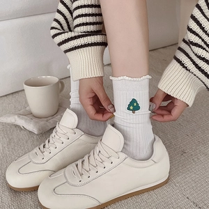 Gros plan de chaussettes blanches en coton avec broderie sapin et bords ondulés