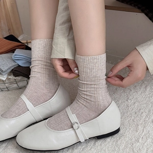 Beige ribbed mid-calf socks for women shown with Mary Jane shoes on white plush rug