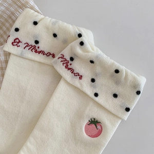 Close-up of cream knit socks with cute tomato embroidery and polka dot fold-over cuffs