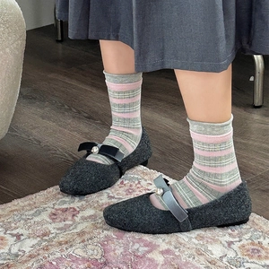 Dettaglio calze a righe con scarpe Mary Jane con perle e gonna grigia a pieghe