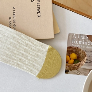 Detail of ribbed knit cotton socks with mustard yellow toe contrast in cream white