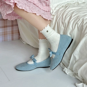 Close-up of light blue Mary Jane flats with bow detail and velvet texture for women