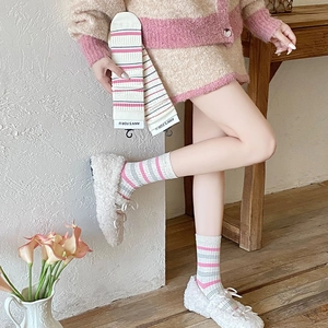 Detailed texture of pink striped crew socks with knit ribbing and branded packaging