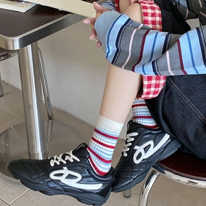 Detailed close-up of retro black sneakers with white geometric logo and striped crew socks