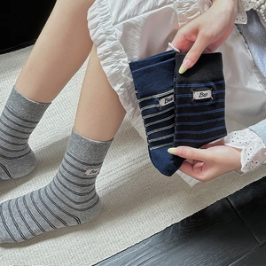 Detail of striped cotton crew socks with embroidered Bee patch in grey, navy, and black