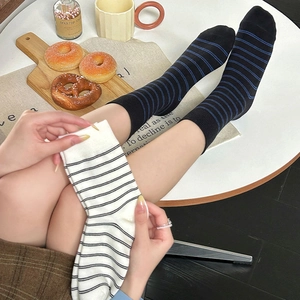 Detail of striped cotton crew socks shown in a cozy lifestyle cafe setting