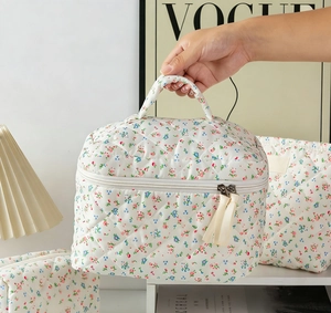 Detail of floral quilted makeup bag with double zippers and elegant tassel handle