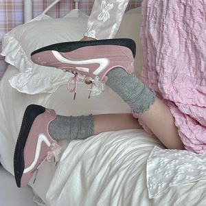 Detail of pink suede balletcore sneakers with sheer bow laces and wavy white trim