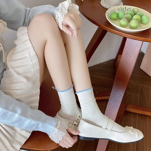 Close-up of cream crew socks with blue wavy edges and heart jacquard pattern on feet
