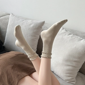 Dettaglio di calze a coste beige con eleganti polsini a doppio volant indossate dal modello