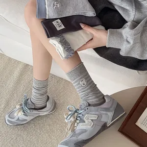 Détail de chaussettes grises rayées brodées et baskets rétro pour un look décontracté