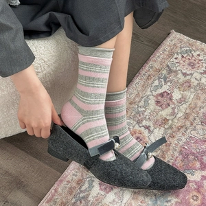 Dettaglio calze a righe rosa e grigie con scarpe Mary Jane pelose e perle lucide