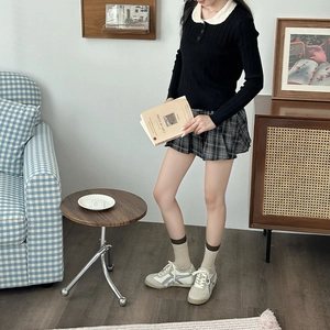 Close-up of grey and blue contrast crew socks paired with pleated skirt and sneakers