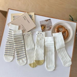 Detail of cream white cotton crew socks with ribbed textures and stripe patterns