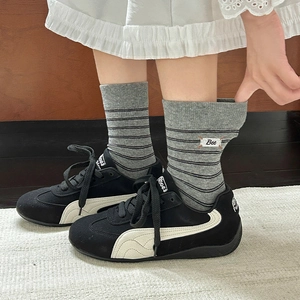 Detail of vintage striped crew socks with Bee embroidery and black suede sneakers