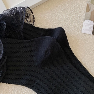 Nahaufnahme von schwarzen Lolita-Socken mit Spitzenbesatz und vertikaler Streifenstruktur