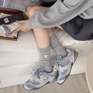 Détail de chaussettes rayées grises avec broderie d'ours et baskets bleues