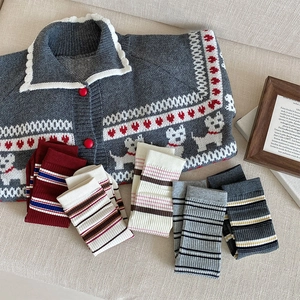 Close-up of gray knit cardigan with dog patterns and various striped socks set