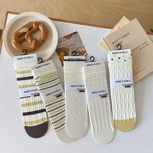 Detail of 5 pairs of textured cream crew socks with stripes and dots in warm autumn tones
